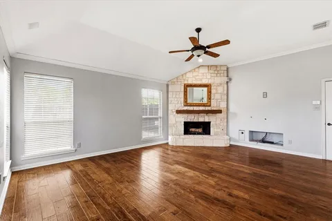 an empty room with windows fireplace and wooden floor
