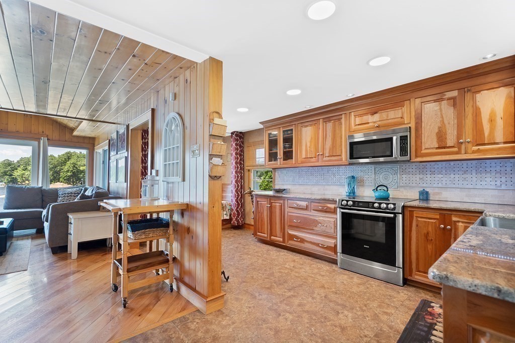 40 Over The Top Road Holland, MA 01521 - Photo 13 of 41 a kitchen with stainless steel appliances granite countertop a stove top oven a sink dishwasher a dining table and chairs with wooden floor