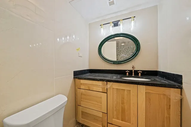 a bathroom with a granite countertop toilet a sink and a mirror