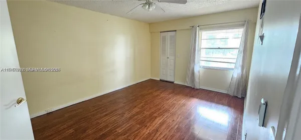a view of empty room with wooden floor and fan