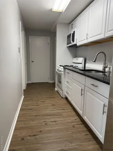 a kitchen with granite countertop a stove top oven a sink and dishwasher with wooden floor