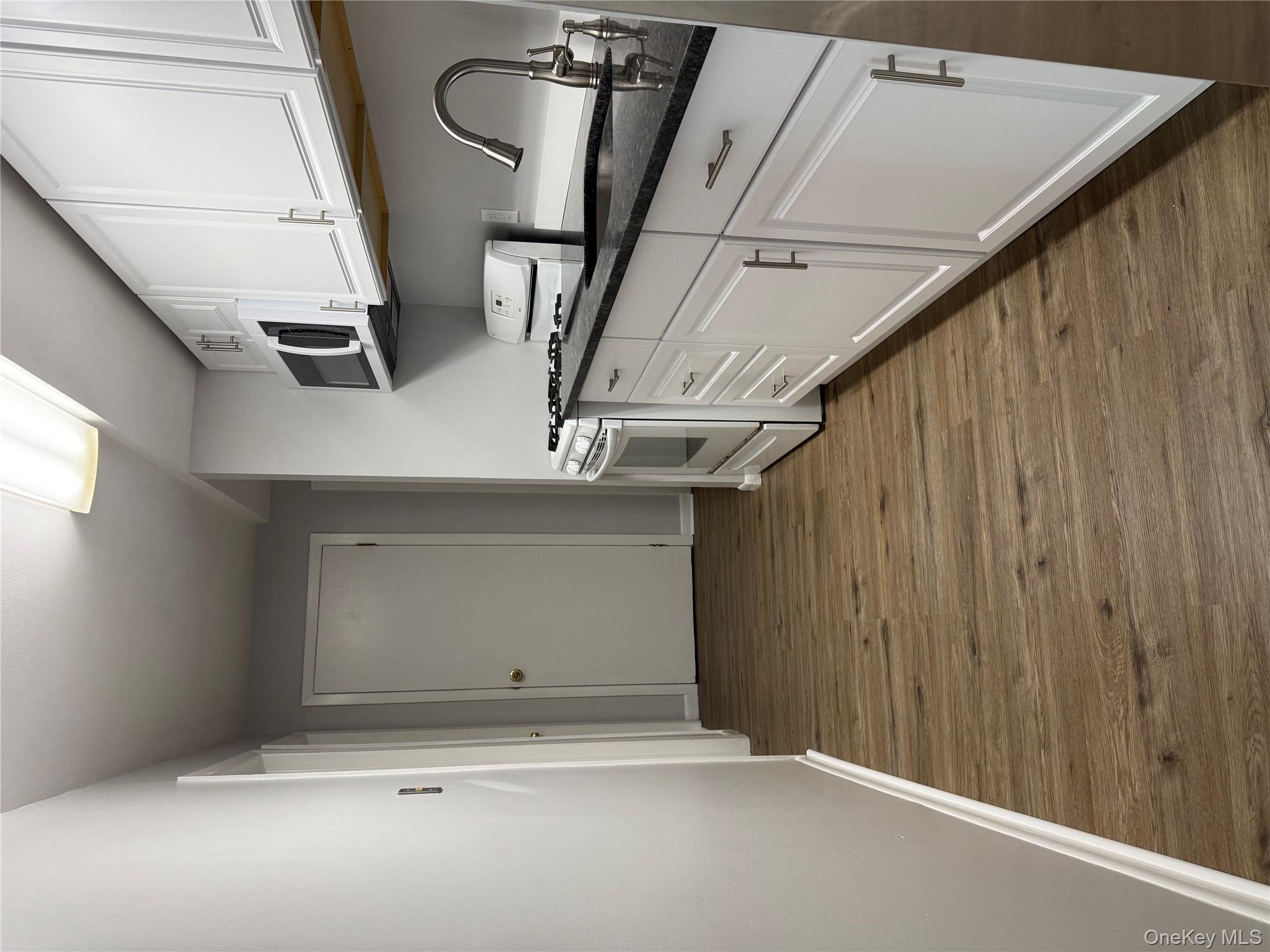 a kitchen with granite countertop a stove top oven a sink and dishwasher with wooden floor