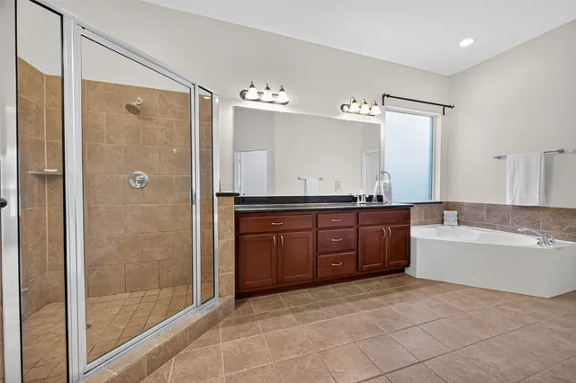 a bathroom with a granite countertop sink a mirror a bathtub and shower