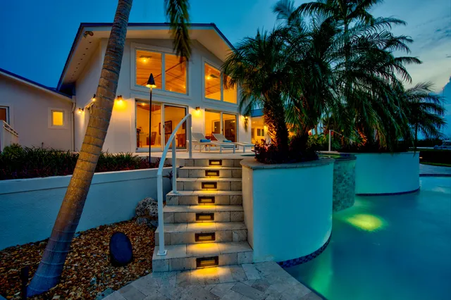 a large white kitchen with stainless steel appliances granite countertop a stove a sink a dining table and chairs