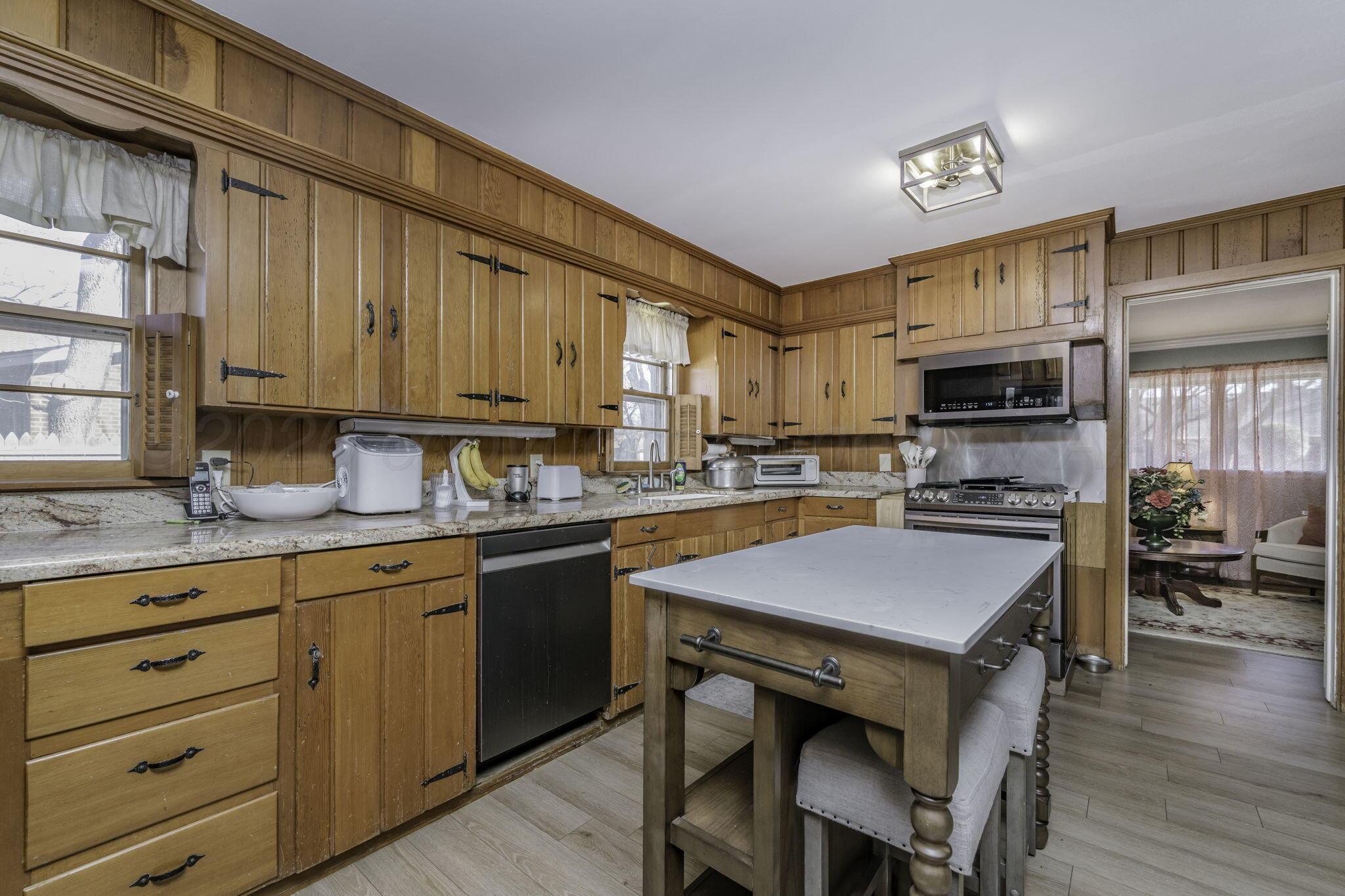 3228 South Travis Street Amarillo, TX 79109 - Photo 7 of 22 a kitchen with granite countertop wooden cabinets a stove top oven a sink and dishwasher