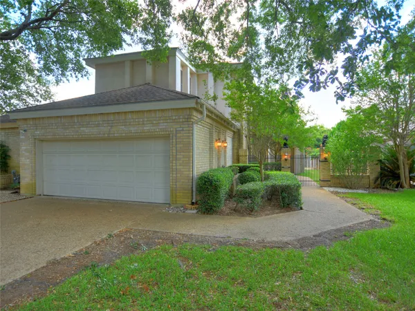 a view of a house with a yard plants and large tree