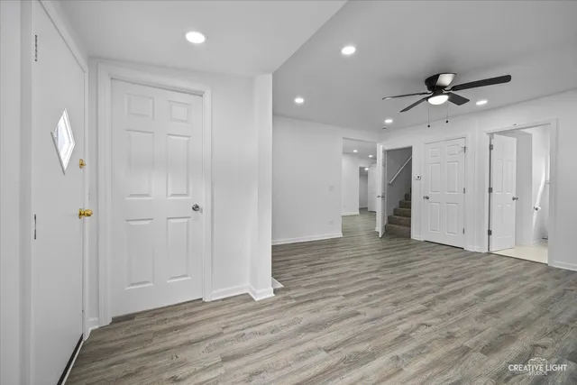a view of an empty room with wooden floor and a ceiling fan