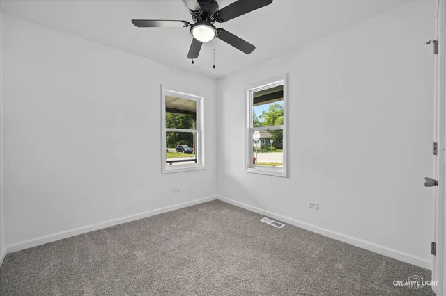 an empty room with windows and fan