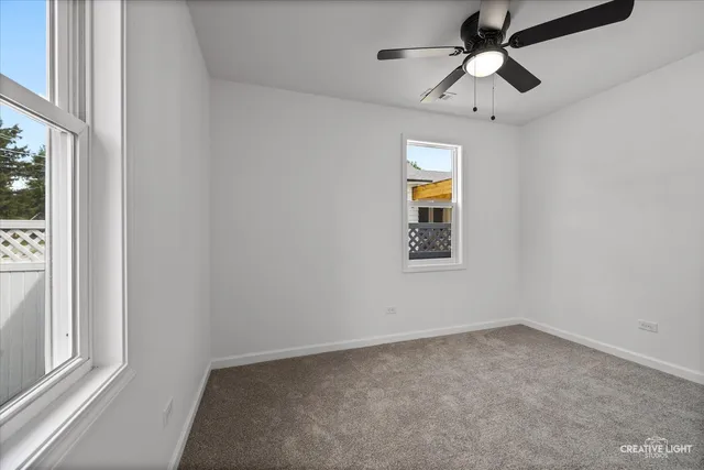 en empty room with windows and ceiling fan
