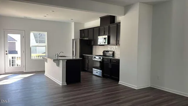 a kitchen with granite countertop a refrigerator and a stove top oven