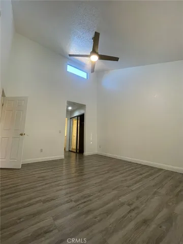 a view of an empty room with wooden floor ceiling fan
