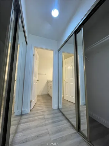 a view of a hallway with wooden floor and a bathroom