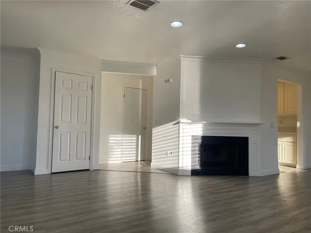 an empty room with wooden floor fireplace and windows