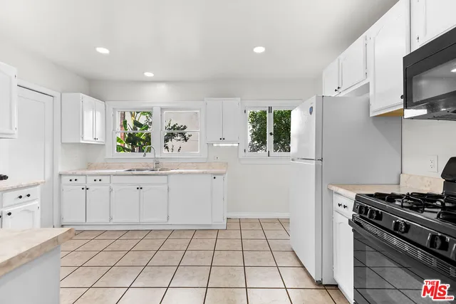 a kitchen with white cabinets appliances and a window