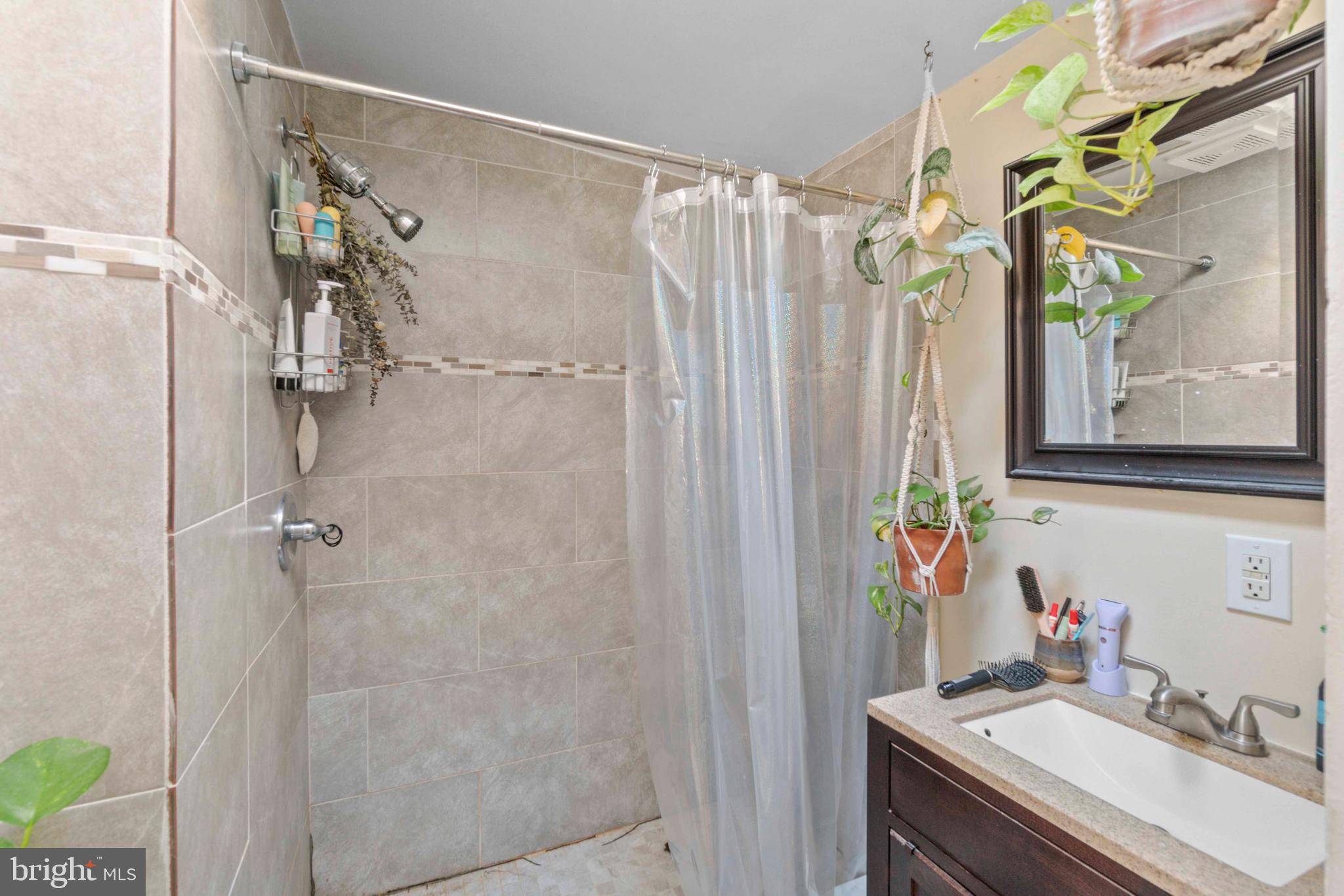 5009 Roland Avenue Baltimore, MD 21210 - Photo 27 of 35 a bathroom with a granite countertop shower a sink and a mirror