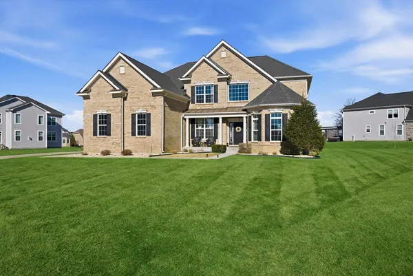 a front view of a house with a yard and green space