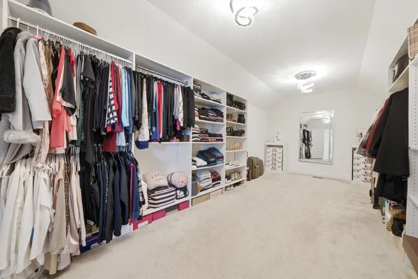 a view of walk in closet with clothes and shoes