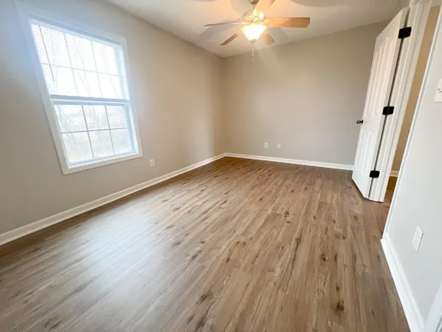 an empty room with wooden floor and windows