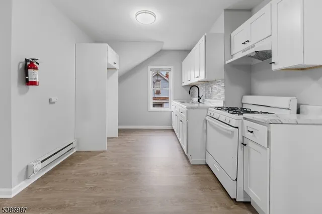 a kitchen with granite countertop a sink stove and cabinets