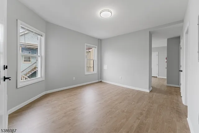 a view of an empty room with a window and wooden floor