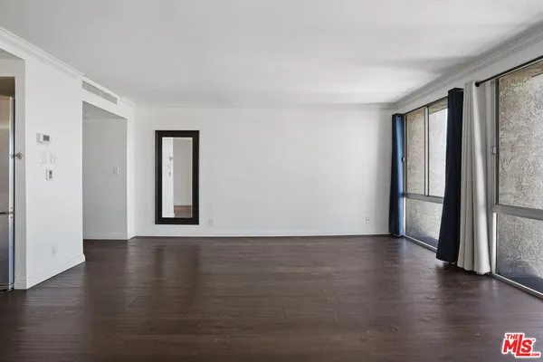a view of an empty room with a window and wooden floor