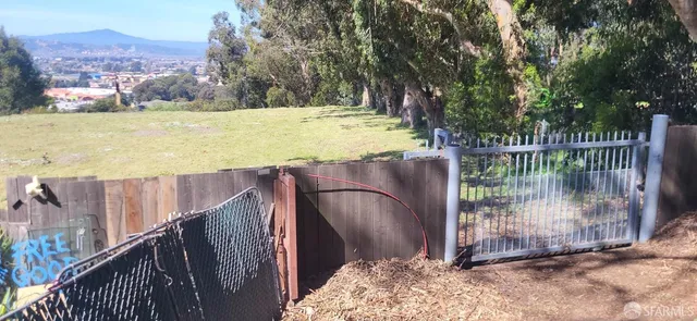 a view of a backyard with a garden and wooden fence