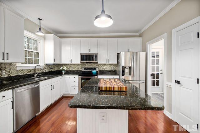 a kitchen with stainless steel appliances granite countertop a sink a stove a microwave a refrigerator a counter space and cabinets