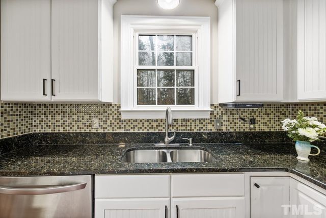 a kitchen with granite countertop a sink and a white wooden cabinets