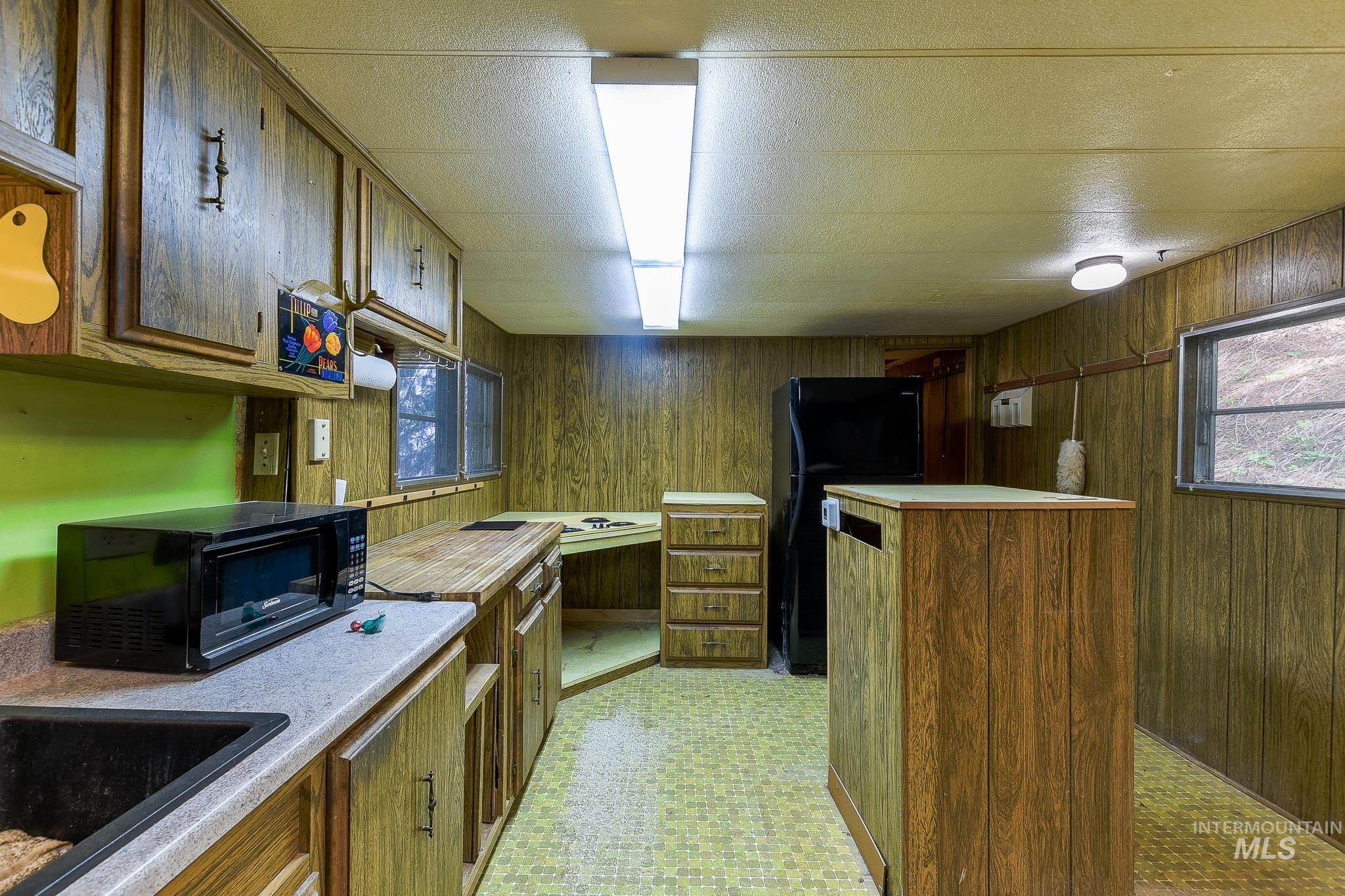 1206 Idlers Rest Road Moscow, ID 83843 - Photo 11 of 47 Kitchen with wood-look paneled walls and ceiling, featuring built-in cabinetry, laminate countertops, and a central island