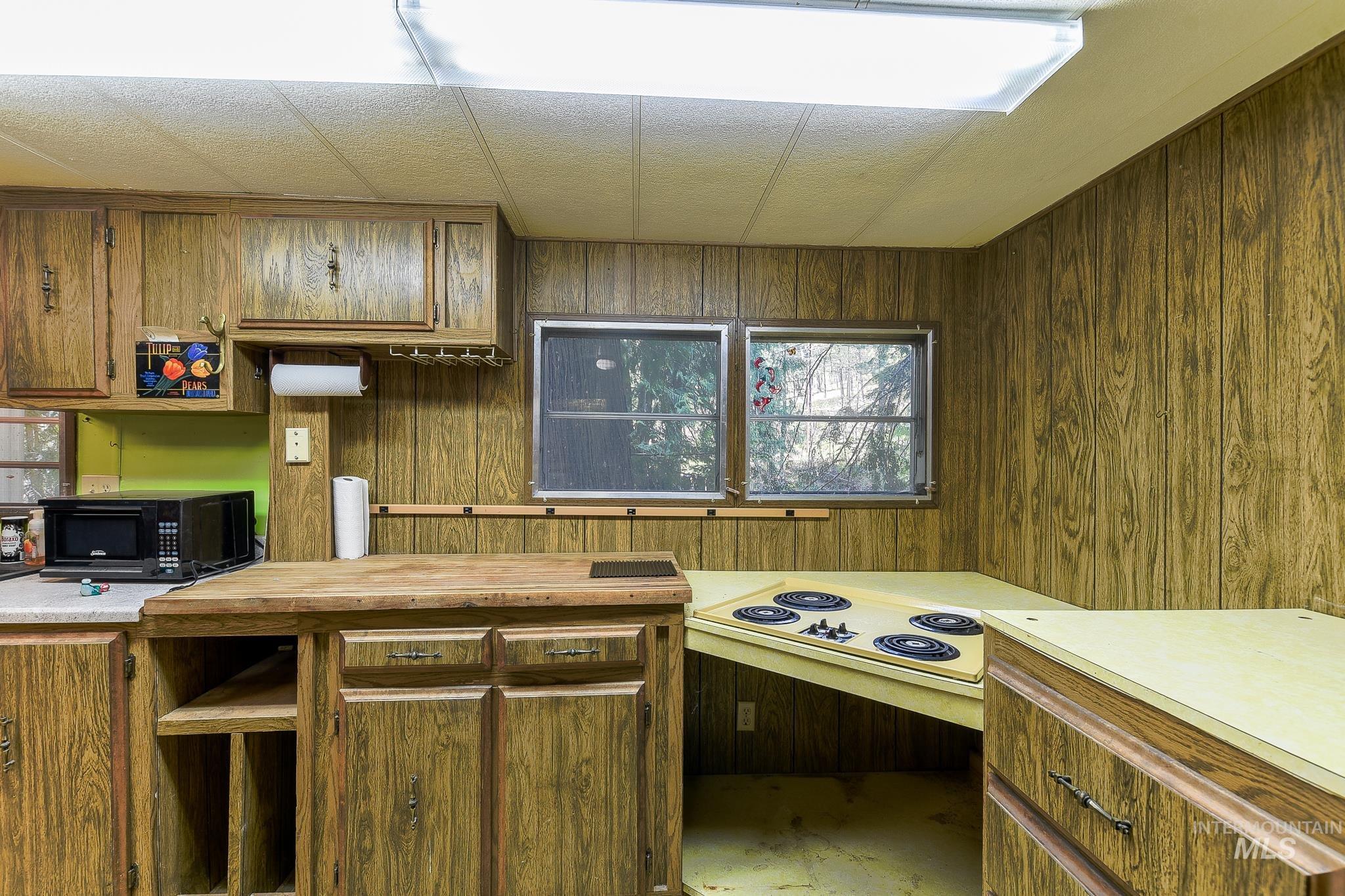 1206 Idlers Rest Road Moscow, ID 83843 - Photo 12 of 47 Kitchen featuring wood-paneled walls, wood-finish cabinetry, a built-in cooktop, and two windows