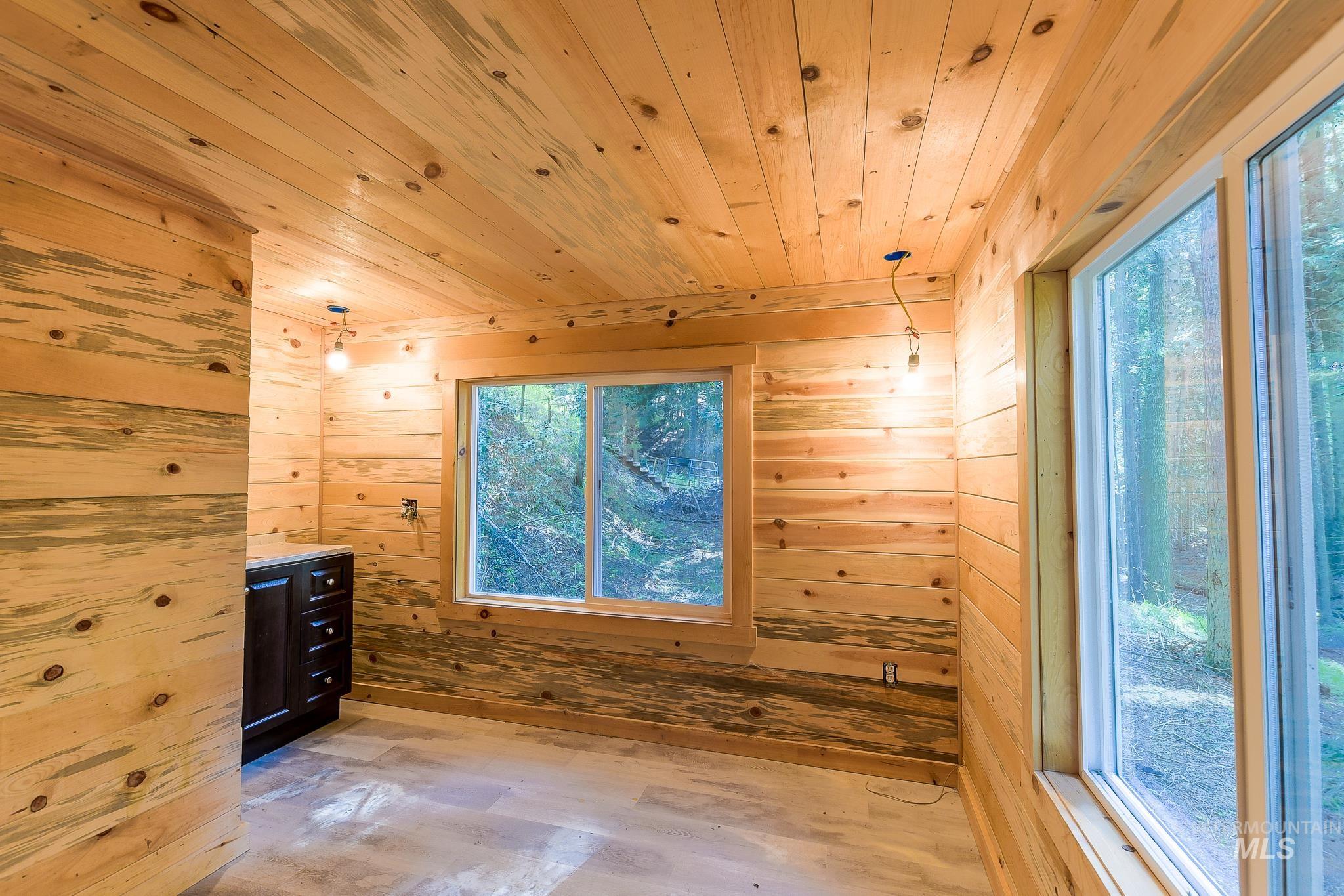 1206 Idlers Rest Road Moscow, ID 83843 - Photo 15 of 47 Room featuring extensive knotty pine paneling on walls and ceiling, two large window openings with forest scenery, and a dark wood-finish vanity with drawer storage