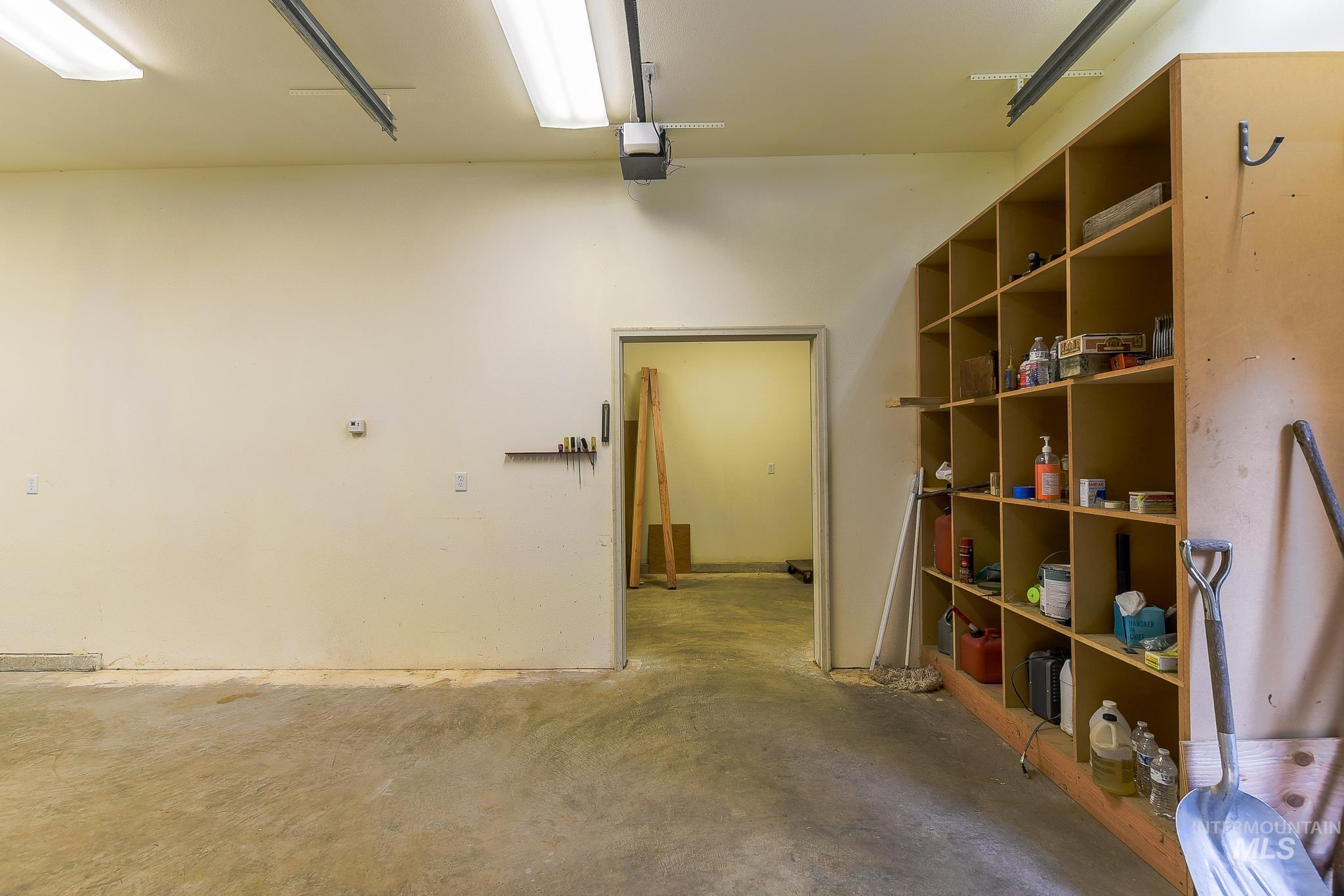 1206 Idlers Rest Road Moscow, ID 83843 - Photo 28 of 47 Spacious garage featuring a concrete floor, built-in shelving, overhead fluorescent lighting, and a neutral wall color