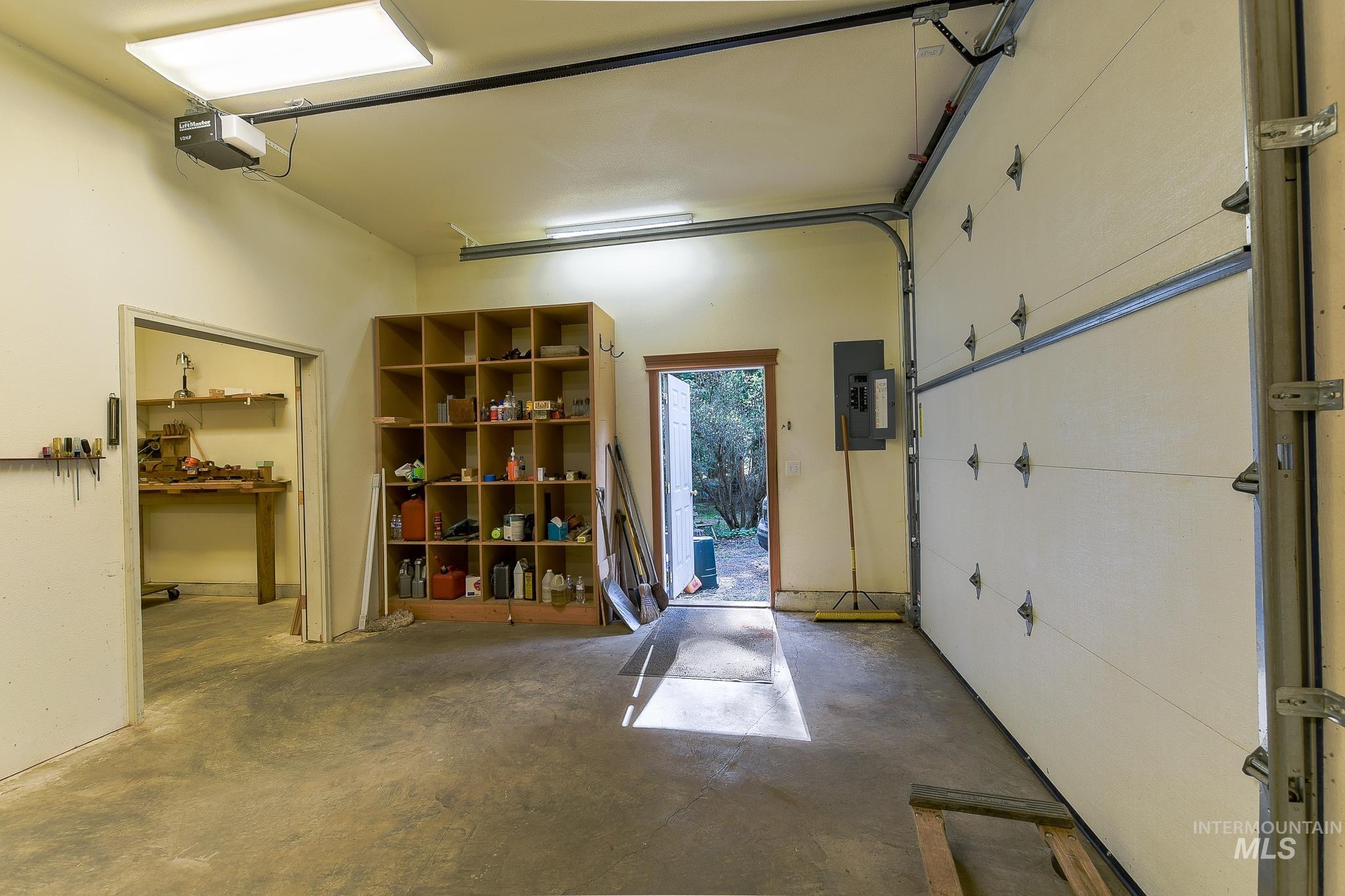 1206 Idlers Rest Road Moscow, ID 83843 - Photo 30 of 47 Spacious garage featuring a motorized overhead door, fluorescent ceiling light fixture, concrete flooring, and built-in wooden shelving