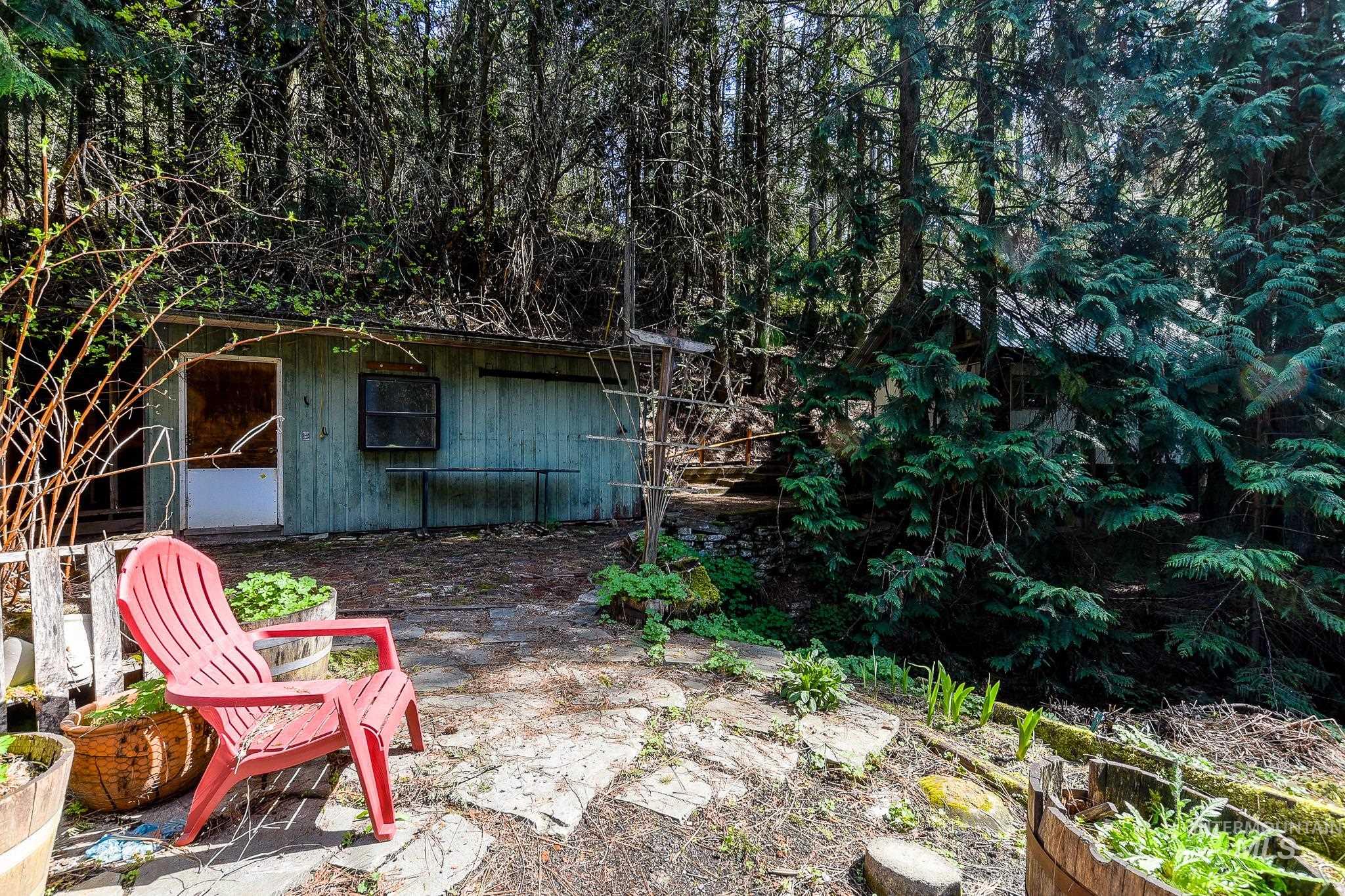 1206 Idlers Rest Road Moscow, ID 83843 - Photo 40 of 47 Stone patio area featuring a detached structure with a single window and door, surrounded by mature trees