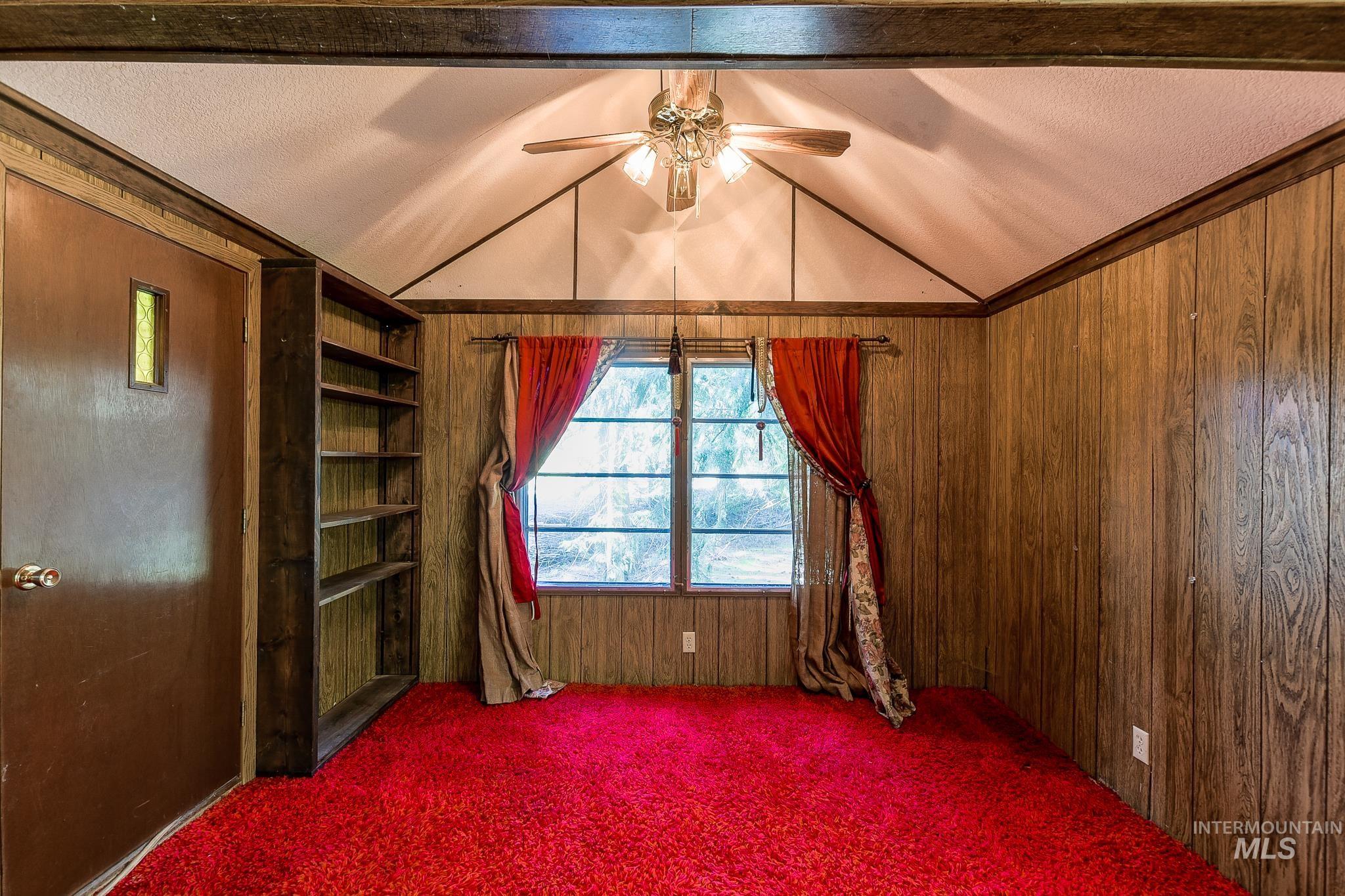 1206 Idlers Rest Road Moscow, ID 83843 - Photo 5 of 47 Room featuring wood-finish paneling, vaulted ceiling, and a built-in wooden bookcase