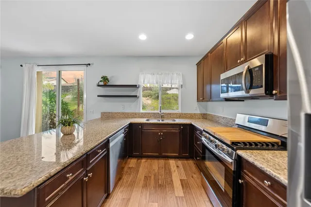a kitchen with stainless steel appliances granite countertop a stove a sink and a microwave