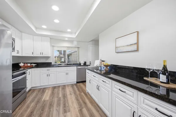 a kitchen with stainless steel appliances white cabinets and wooden floors