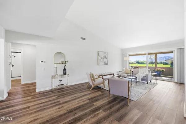 a living room with furniture large window and wooden floor
