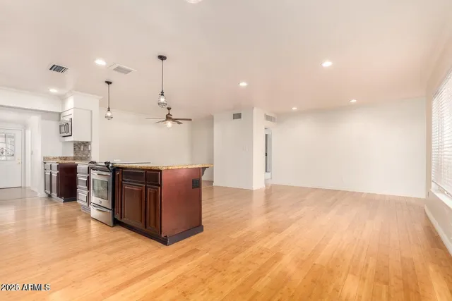a living room with stainless steel appliances kitchen island wooden floors cabinets and couches