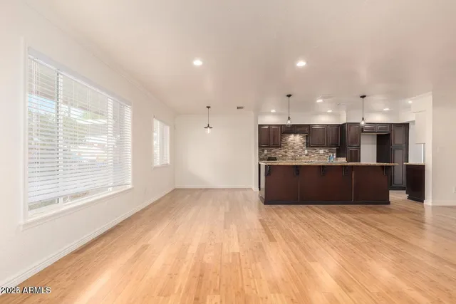 a view of kitchen with kitchen island a sink wooden floor and a refrigerator