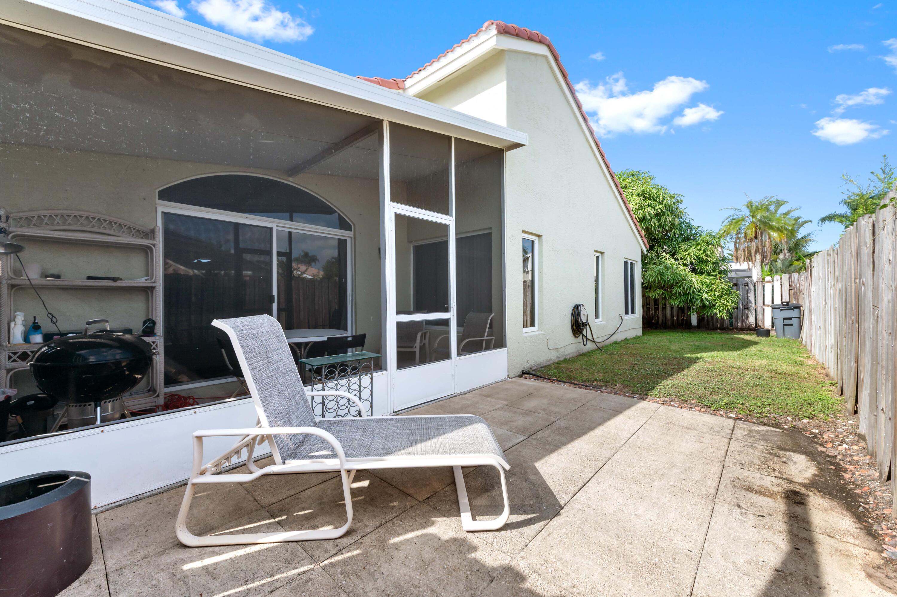 7409 Michigan Isle Road Lake Worth, FL 33467 - Photo 35 of 43 a view of a patio with table and chairs and a barbeque