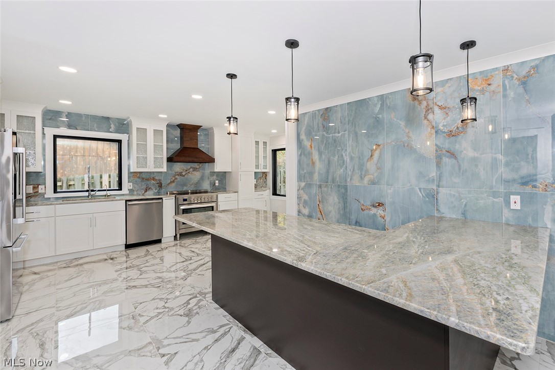 20601 Shelburne Road Shaker Heights, OH 44122 - Photo 9 of 29 Kitchen with pendant lighting, light marble finish floors, white cabinets, glass insert cabinets, and crown molding
