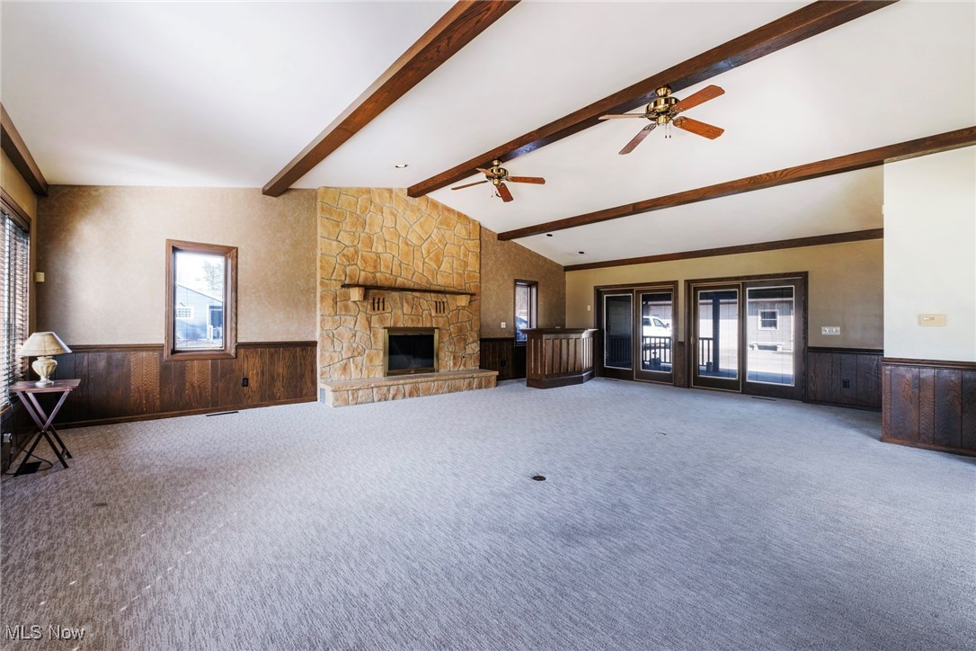 7059 Stewart Sharon Road Hubbard, OH 44425 - Photo 8 of 49 Unfurnished living room featuring lofted ceiling with beams, carpet, a wainscoted wall, and wood walls