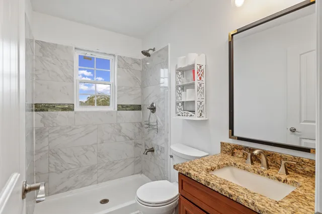 a bathroom with a granite countertop sink toilet and shower