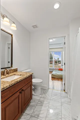 a bathroom with a granite countertop sink a toilet and a mirror
