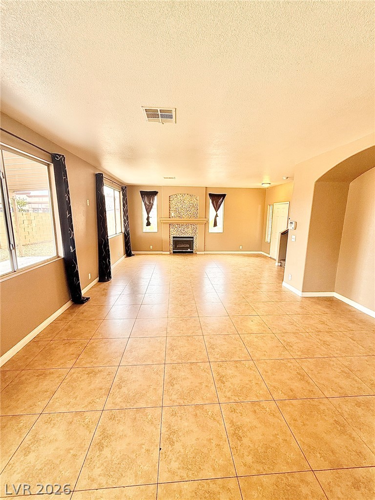 4313 Ranch Foreman Road North Las Vegas, NV 89032 - Photo 6 of 27 An open living space features tile flooring and a central fireplace focal point.