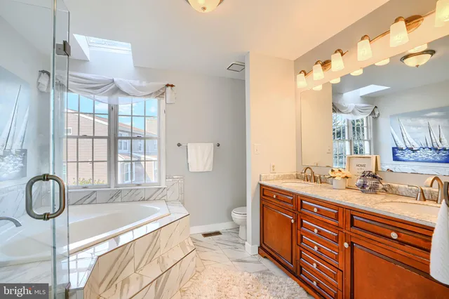 a spacious bathroom with a double vanity sink toilet mirror and bathtub
