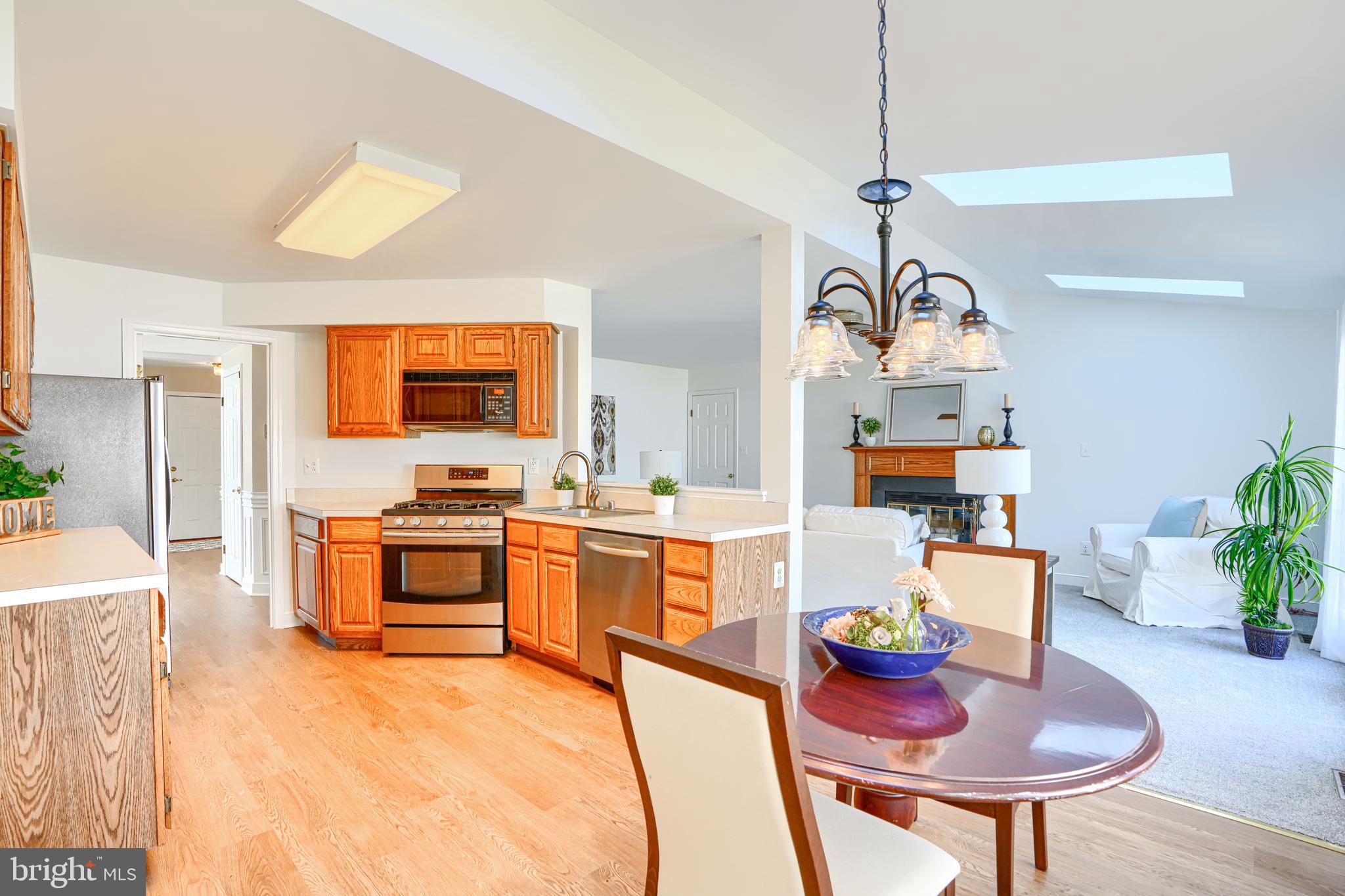 9018 Gardenia Road Baltimore, MD 21236 - Photo 3 of 47 a kitchen with stainless steel appliances kitchen island granite countertop a sink a stove a dining table and chairs with wooden floor