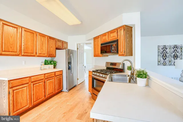 a kitchen with stainless steel appliances granite countertop a stove a sink dishwasher and a refrigerator with wooden cabinets