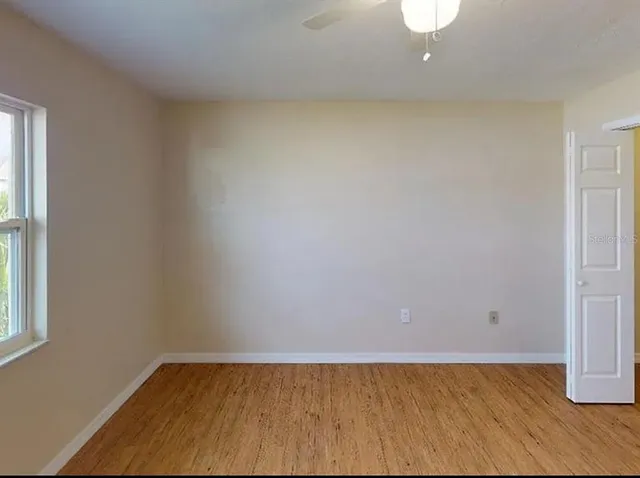 a view of an empty room with wooden floor and a window